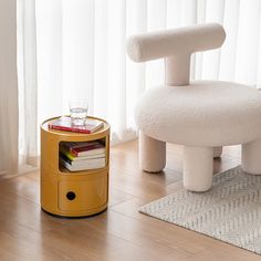 a white chair sitting on top of a wooden floor next to a table with books