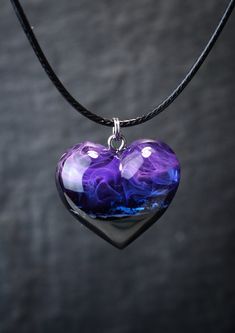 a purple heart shaped glass pendant on a black cord