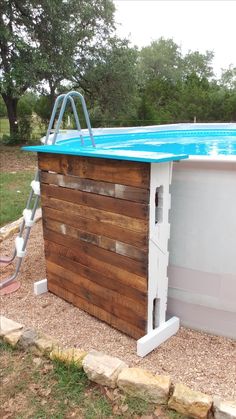 an above ground pool with a wooden fence around it and a ladder to the side