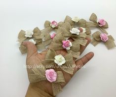 the hand is holding several pieces of burlock with pink and white flowers