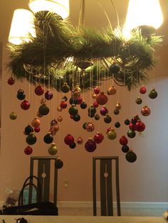 a chandelier with christmas ornaments hanging from it's sides in a dining room