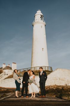 a group of people standing in front of a light house