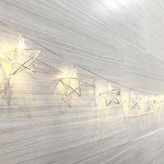 some lights that are on the side of a wall with paper stars attached to it