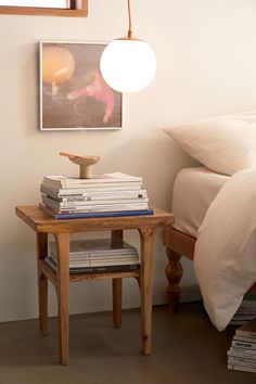 a small table with books on it next to a bed