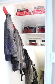 an open closet with clothes hanging on the wall and other items in baskets behind it