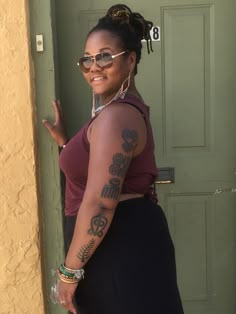 a woman with tattoos on her arm standing in front of a door