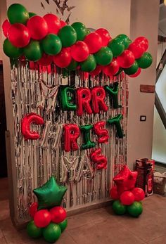 some red and green balloons are hanging on the wall in front of a sign that says merry christmas