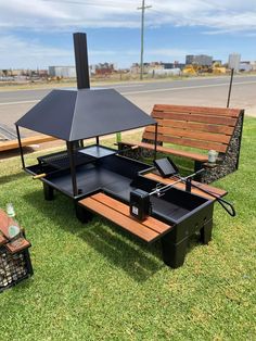 a picnic table with an umbrella on it in the grass next to a park bench