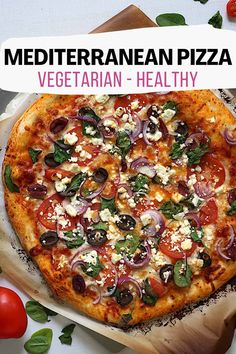 a pizza sitting on top of a wooden cutting board next to tomatoes and other vegetables