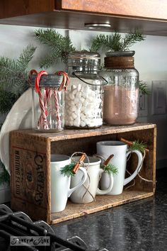 some mugs are sitting on a shelf with candy canes and marshmallows