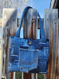 a denim purse hanging on a wooden fence