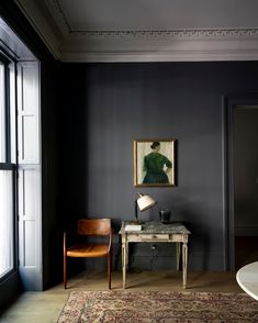 a room with a desk, chair and painting on the wall next to a window