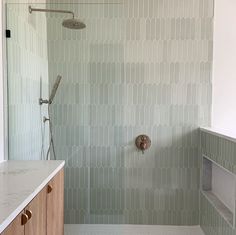 a walk in shower sitting next to a white counter top under a faucet