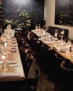 a dining room with long tables and candles on the table, along with flowers in vases