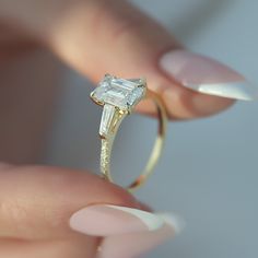 a woman's hand holding an engagement ring with a diamond in the middle and side