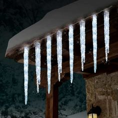 icicles hanging from the roof of a house in the snow at night with lights on