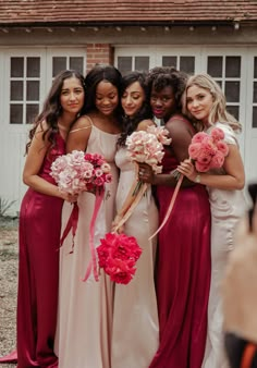 a group of women standing next to each other in dresses and holding bouquets with flowers