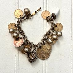 Vintage Coin Charm Bracelet ... this one's a fancy Midcentury gem! Real coins dot the triple ring rolo chain strand. You'll see currency from Great Britain, South Africa, and Switzerland. In the center, a stunner of a  Victorian Charm, it isn't easy to spot, but one of the four stones has gone missing. Textured gold tone metal beads and Chippy acrylic pearls join the party. There's one more dear near the end that somehow makes this bracelet complete, a bright white shark tooth replica in a fancy metal bezel. And with that, you have an Eclectic Boho Chic masterpiece. A truly stunning piece that would make Iris Apfel proud and will catch everyone's eye with each wearing! Measures 7 inches long and closes with a latch clasp. Enjoy ~  Stand out from the crowd Penelope & Anastasia babes and joi Midcentury Eclectic, Coin Charm Bracelet, Triple Ring, Eclectic Boho, Boho Eclectic, Shark Tooth, Rolo Chain, Gold Texture, Metal Beads