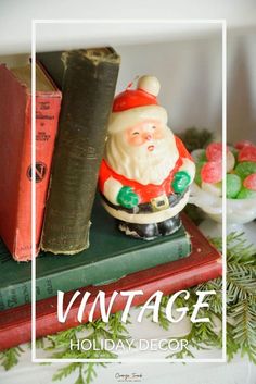 a santa clause figurine sitting on top of a book next to some christmas decorations