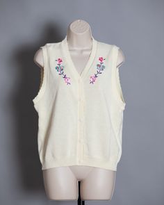 Cute womens 70s 80s button front knit vest. Cream color with pretty flower and butterfly design. S.G. SPORT Collection size - Medium vintage pre-owned Retro V-neck Vest For Spring, Vintage V-neck Vest For Spring, Retro V-neck Spring Vest, Spring V-neck Retro Vest, Vintage V-neck Sweater Vest For Spring, Retro Spring Vest, Spring Vintage Vest, Retro Cotton Sweater Vest For Spring, Vintage Sleeveless Sweater Vest For Spring