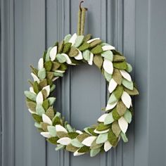 a green and white wreath hanging on the front door, with leaves painted on it