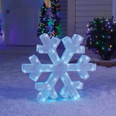 a lighted snowflake in front of a house