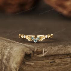 a gold ring with leaves and blue topazte stones sits on an old book