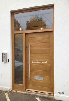 a wooden door with glass on the side of a white wall next to a parking lot