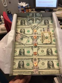 someone is holding up a box made out of one hundred dollar bills and gold coins