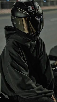 a person wearing a motorcycle helmet and sitting on a motorbike in the street