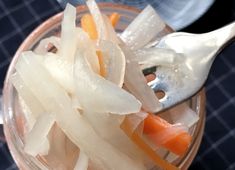 a spoon with some food in it on top of a glass bowl filled with liquid