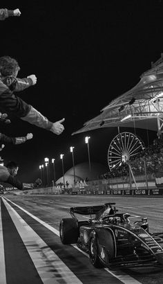 two men jumping over a car on top of a race track at night with people watching from the stands