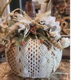 a crocheted pumpkin decorated with flowers and greenery is sitting on some hay