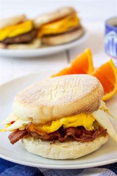 a breakfast sandwich on a plate with oranges and other food items in the background