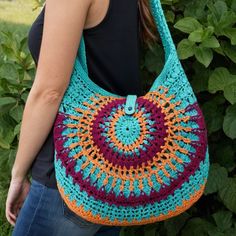 a woman carrying a crocheted bag in front of bushes