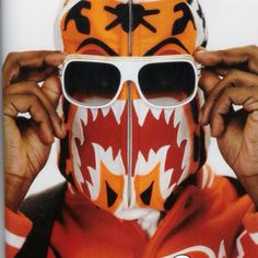 a man wearing sunglasses and a tiger mask with his mouth painted like a football helmet