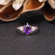 Amethyst Engagement Ring Unique Triangle Cut Moissanite Cluster Wedding Ring Art Deco Pear Shaped Purple Gemstone Rose Gold Bridal Ring RING DESCRIPTION ✦Engagement Ring ✴Center Stone - Amethyst Shape - Pear Cut Size - 6x8mm ✴Side Stones - Moissanite & Alexnadrite Shape - Triangle & Round Cut Weight - 0.26ct ✴Band Width - About 1.5mm ✴Ring Metal: Available in rose gold plated, yellow gold plated, 925 sterling silver, 10k or 14k solid rose, yellow or white gold. MAKING & SHIPPING ✦PAYMENT PLAN ♡ Pear-shaped Three Stone Jewelry For Anniversary, Purple Diamond Cut Jewelry For Wedding, Rose Gold Solitaire Amethyst Wedding Ring, Wedding Diamond Ring With Trillion Cut Center Stone, Pear-shaped Diamond Ring With Accent Stones For Wedding, Purple Three Stone Wedding Jewelry, Purple Pear-shaped Ring With Prong Setting, Trillion Cut Solitaire Jewelry For Wedding, Amethyst Diamond Ring With Center Stone For Wedding