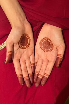 two hands with hendi designs on them, one is painted brown and the other is red