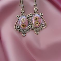 Victorian-inspired earrings, featuring genuine light pink dried flowers sourced from Armenia. These handcrafted antique aesthetic earrings are designed to infuse your look with a touch of timeless elegance and a dash of romance. Each pair of earrings is a unique work of art, carefully crafted to capture the essence of vintage charm. The delicate, preserved pink flowers add a touch of nature's beauty to your accessory collection, making them a perfect choice for nature lovers and those who apprec Pink Flower Earrings As Gift, Vintage Flower Drop Earrings For Gift, Vintage Flower Earrings With Ear Wire, Handmade Vintage Rose Gold Earrings, Vintage Flower Shaped Nickel Free Earrings, Bohemian Drop Earrings With Natural Inclusions, Pink Metal Flower Earrings For Gift, Vintage Rose Gold Drop Earrings, Rose Gold Vintage Flower Earrings For Gift