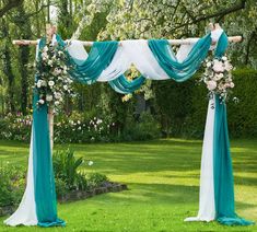 an outdoor wedding ceremony with blue and white draping, flowers and greenery