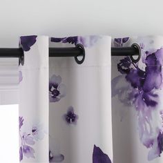 purple flowers are on the curtain rod in front of a window with white curtains and black hardware