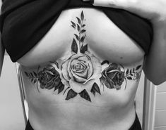 a woman's stomach with roses and leaves tattooed on the side, in black and white