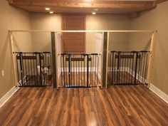 an empty room with wooden floors and two gates on each side that are open to allow dogs