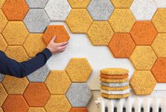 a person is touching the wall with his hand next to some yellow and gray hexagonal tiles