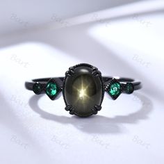 a ring with an oval stone surrounded by green stones