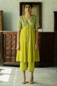 Lime green gathered kurta with floral and geometric printed motifs, cutdana, sequin and bead work. Paired with printed stripe pant.
Component: 2
Printed 
Neckline: V neck
Sleeve Length: Short
Fabric: Georgette, Cotton Silk
Color: Green
Sequin and bead work
Striped pant
Front tassel tie-up - Aza Fashions Blouse Yoke, Striped Pant, Bright Pastels, Green Sequins, Indian Fashion Designers, Kurta With Pants, Silk Pants, Kurta Designs, Kurta Set