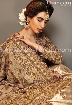 a woman in a gold dress with jewelry on her head and hands resting on her chest