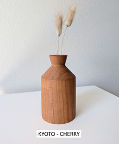 a wooden vase sitting on top of a white table next to a plant in it