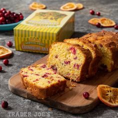 a loaf of cranberry orange bread on a cutting board next to a box of dried cranberries