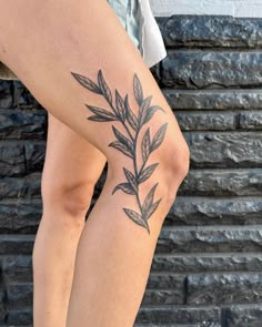 a woman's legs with tattoos on them and leaves in the middle of her leg